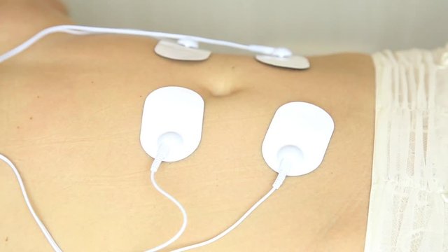 professional electrotherapy on woman body. muscle contraction under the influence of an electric current. close-up patient's stomach