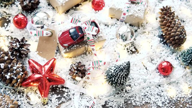 Christmas and New year background with toy car present with ribbon. Balls, pinecones and different decorations on snow.
