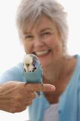 Older woman with blue bird on her finger.