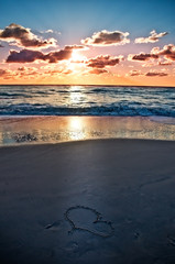 a heart on the beach at sunset