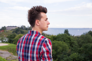 Man in stylish suit looking forward to the sea horizon. Standing on the top of the rock. Finland, Helsinki, islands. 