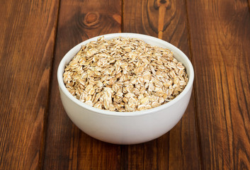 Bowl of oatmeal close-up on background dark wood.