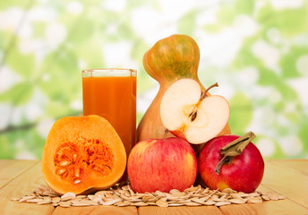 Pumpkin, apple, glass juice and seeds on green abstract.