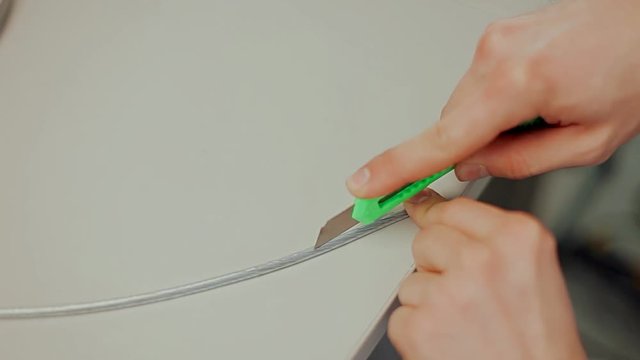 Work with fiber optic cable / Male hands cut off unnecessary insulation from cable and remove screen braid during preparing to installation.