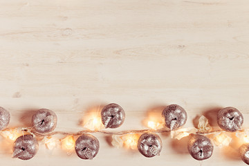 Christmas silver apples decoration and lights burning  on a beige wooden background. Xmas background.