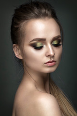 Beautiful woman portrait on grey background with green eye shadows.