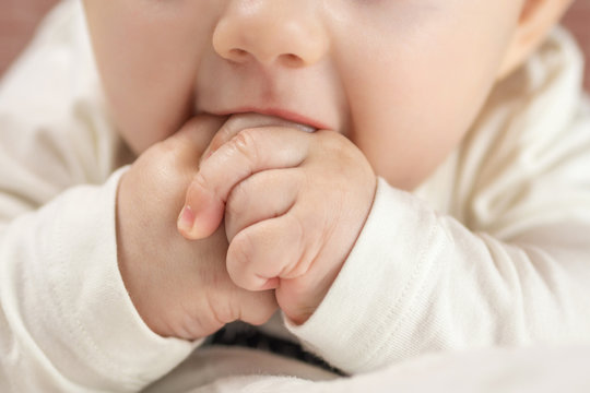 adorable happy baby biting his hands