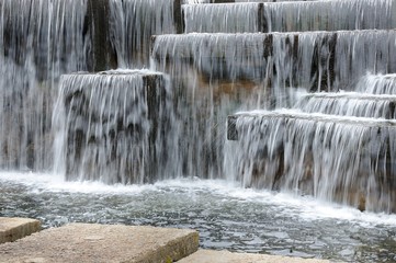 thresholds of artificial waterfall from stone blocks. concrete walking path