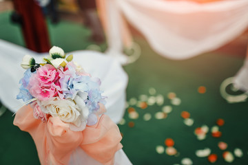 Beautiful white arch with flower decorations for the wedding ceremony on the green background with...
