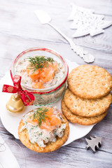 Smoked salmon, soft cheese and dill spread, mousse, pate, rillette in a jar with crackers on white wooden background. Delicious Christmas themed dinner table. Holiday concept.