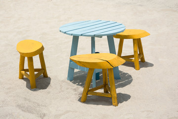 TABLE AND CHAIRS ON SANDY BEACH IN SUNNY DAY