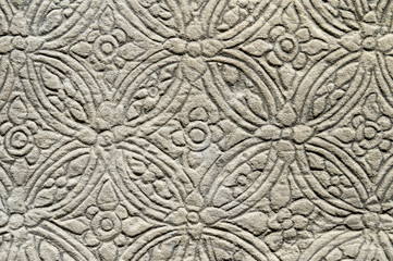 Detail close-up of the textured pattern of a carving in relief on a rough weathered stone wall at the Angkor Wat temple complex in Cambodia