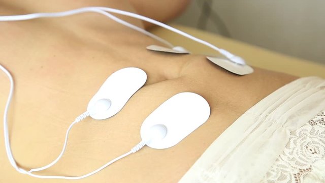 professional electrotherapy on woman body. muscle contraction under the influence of an electric current. close-up patient's stomach