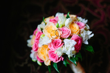 Golden wedding rings on a delicate bouquet. Focus on the rings.