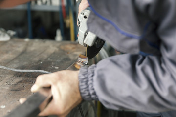 worker grinds metal rods, close up