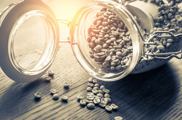 Coffee beans in glass jar on wooden background.