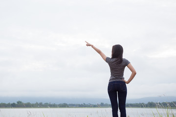 Obraz premium Young Asian fit woman relaxing with the river nature pointing fi