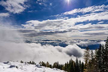 Amazing winter landscape. Cloudy sky, sun, and mountains in snow. Frosty and sunny day in Alps