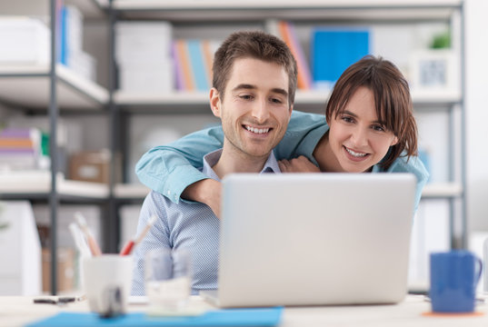 Happy couple at home using a laptop