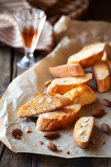 Freshly baked Italian almond cantuccini with a small glass of vin santo at the background in a rustic setting