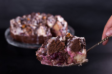 chocolate cake with nuts coated with a glaze on a black background, studio