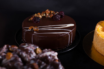 chocolate cake with nuts coated with a glaze on a black background, studio