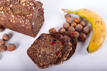 loaf of bread with bananas and hazelnuts on a white background