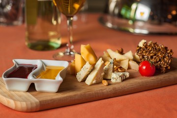 different varieties of cheese with honey and jam on a wooden tray