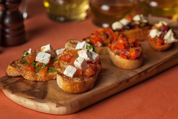 delicious toast with cheese, tomatoes and herbs on a wooden tray