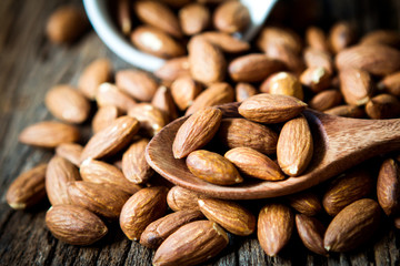 close up Peeled almonds nut in spoon on wooden  background