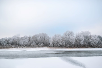 Winter landscape of snow-covered fields, trees and river