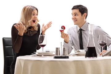 Young guy proposing to his girlfriend at a restaurant table