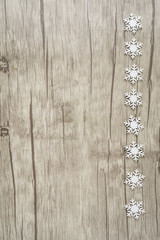 Ein Holzuntergrund mit Schneekristallen am rechten Bildrand, vertikal mit Textfreiraum