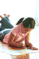 Obraz na płótnie Canvas Girl lying on floor, drawing with crayons