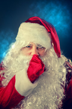 Santa Claus presses a finger to his lips.