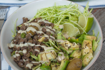 Green raw vegan zucchini pasta with lentils, pesto, tahini, avocado, olives and oil. Delicious food detox every day.
