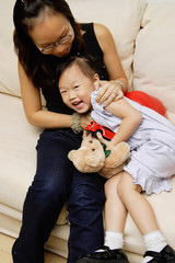 Mother and daughter on sofa, daughter smiling  at camera