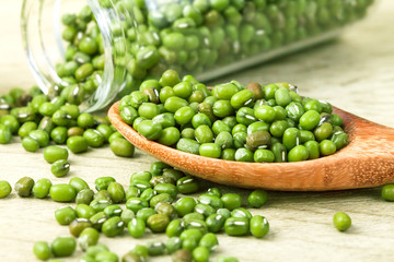 close up green mung beans in wooden spoon on wood plate