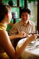 Man holding woman's hand in restaurant, ring on her finger