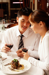 Couple in restaurant, sitting side by side, holding hands