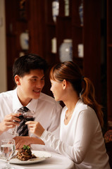 Couple in restaurant, toasting with wine glasses
