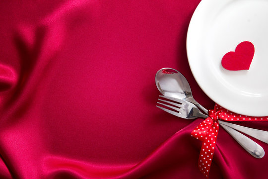 red heart shape with White empty plate with fork and spoon 