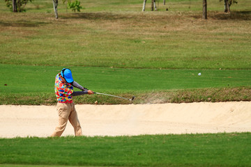 The golfers hit golf balls off the sand motion blur