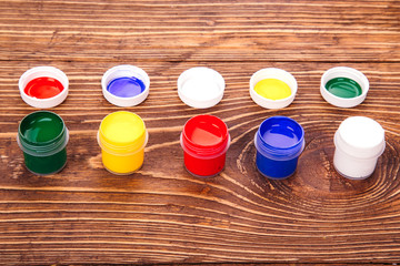 acrylic paints in jars, on the retro wooden background