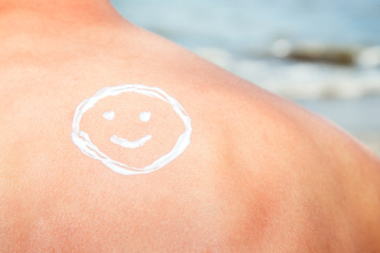 Lotion man with sunscreen smiley above sea background