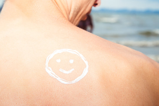Lotion man with sunscreen smiley above sea background