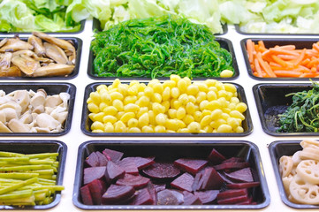 Various vegetables mixed on salad bar.
