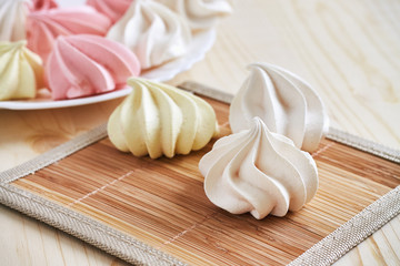 Fresh delicious colored meringue cookies on wooden table
