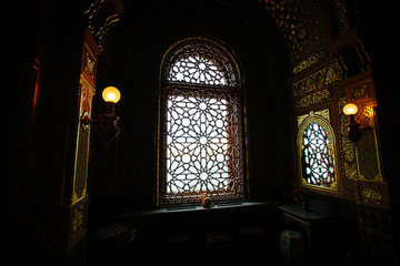 The interior in the Moorish style, dim lights. Window with tracery lattice