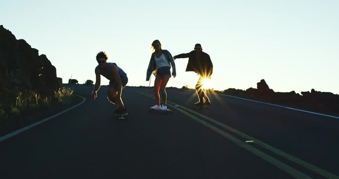 Skateboarders riding down mountain road